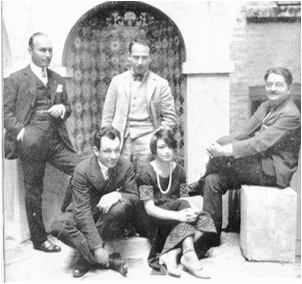 Black and white photo of 5 people casually posing for the camara. 